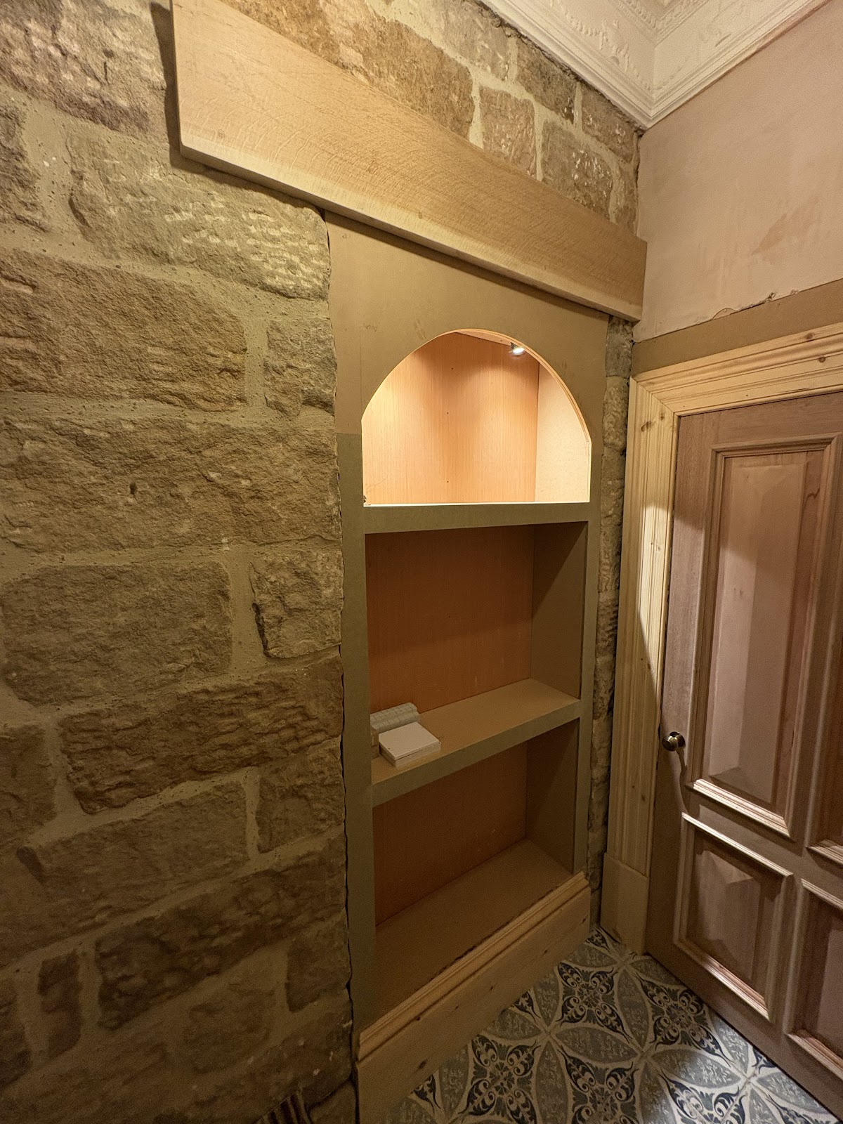Bespoke arched alcove shelving built into an exposed stone wall
