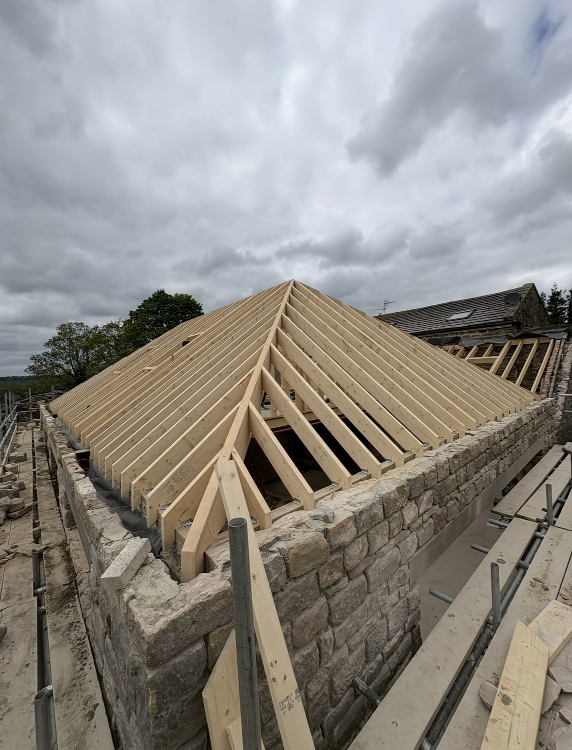 Large hip-roof timber truss structure on a stone building