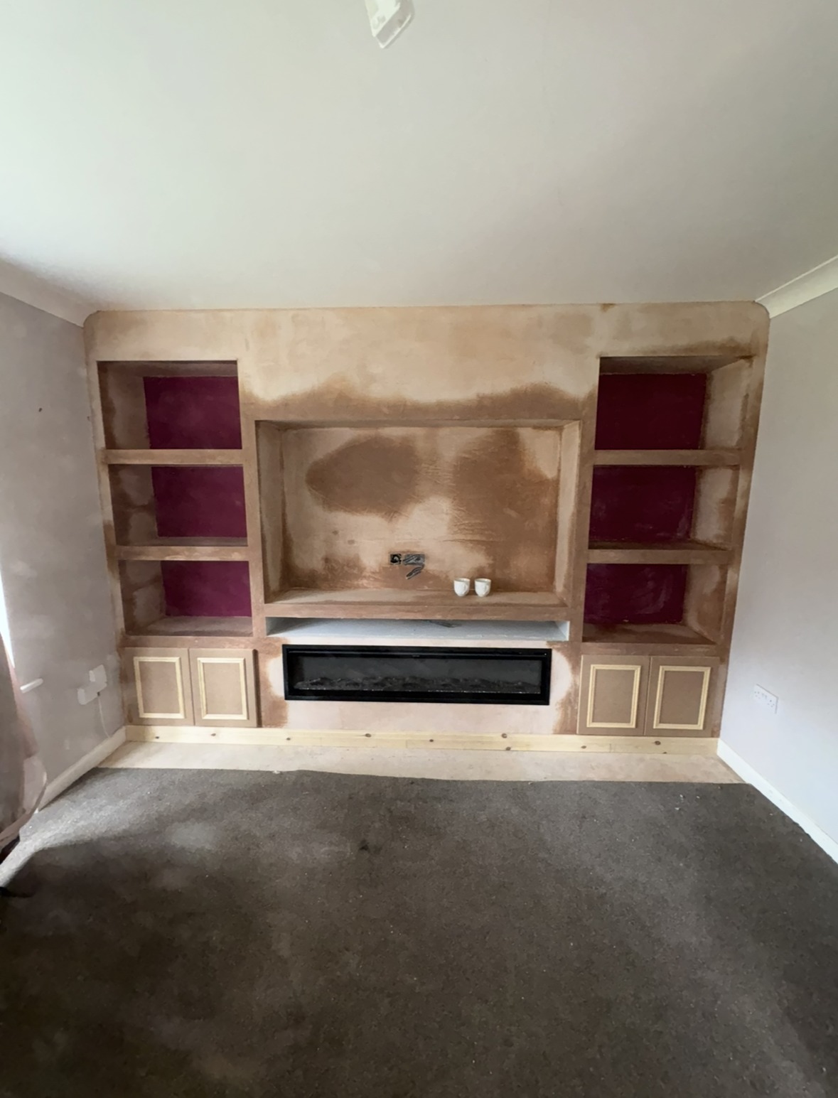 Fitted alcove shelving either side of a fireplace, ready for painting